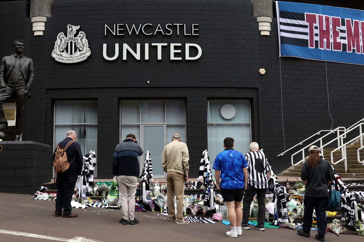 People stop to look at floral tributes and scarves outside St James' Park for Kevin Keegan in Newcastle