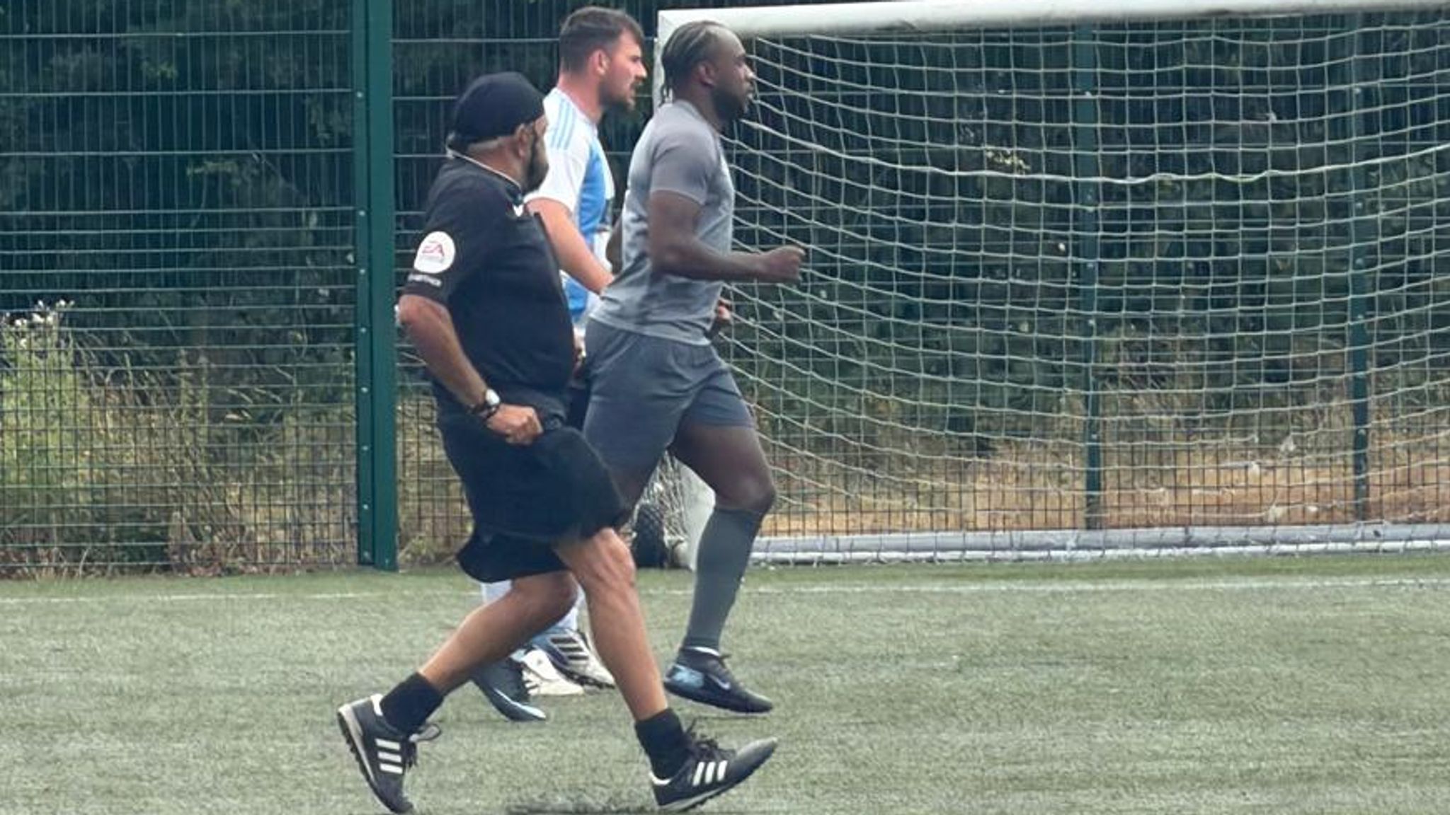 Michail Antonio and an opposition player are tracked by referee Jarnail Singh at KFF tournament Leicester