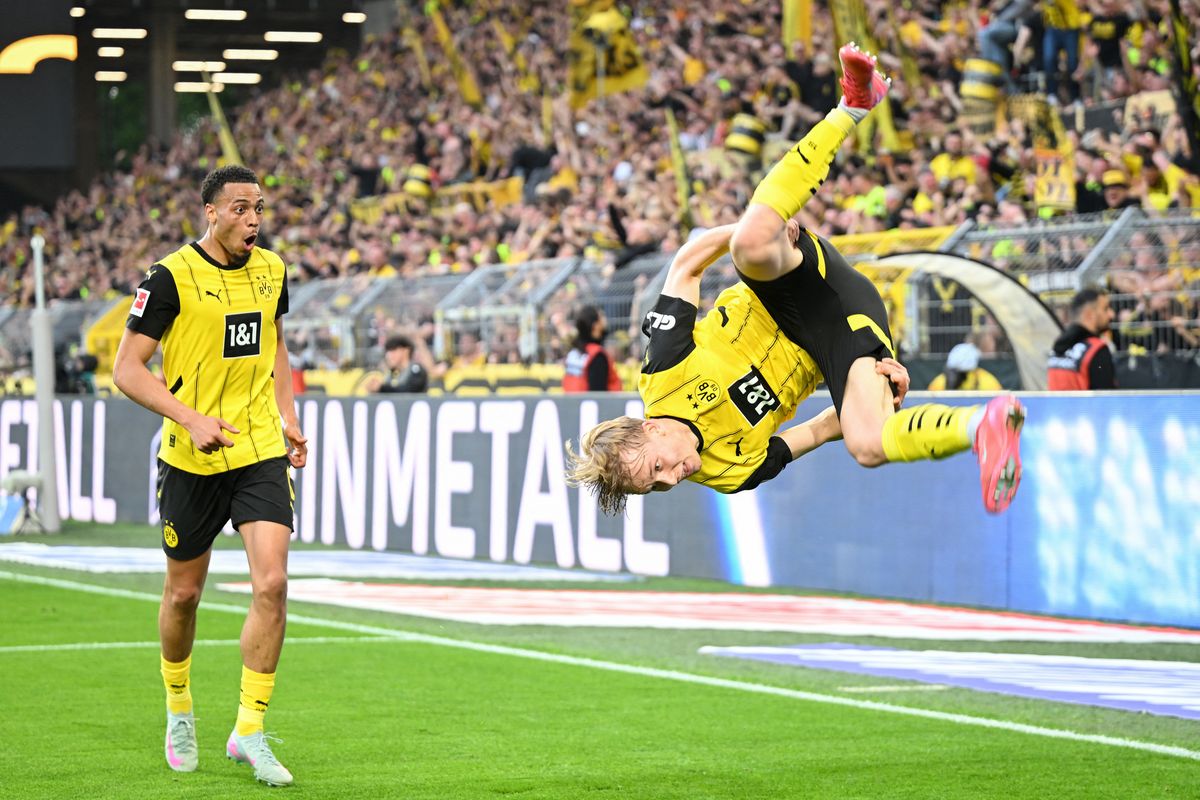 Dortmund's German midfielder #08 Felix Nmecha (L) watches as Dortmund's Swedish defender #24 Daniel Svensson (R) celebrates scoring the 3-1 goal by making a somersault during the German first division Bundesliga football match BVB Borussia Dortmund vs Borussia Moenchengladbach in Dortmund