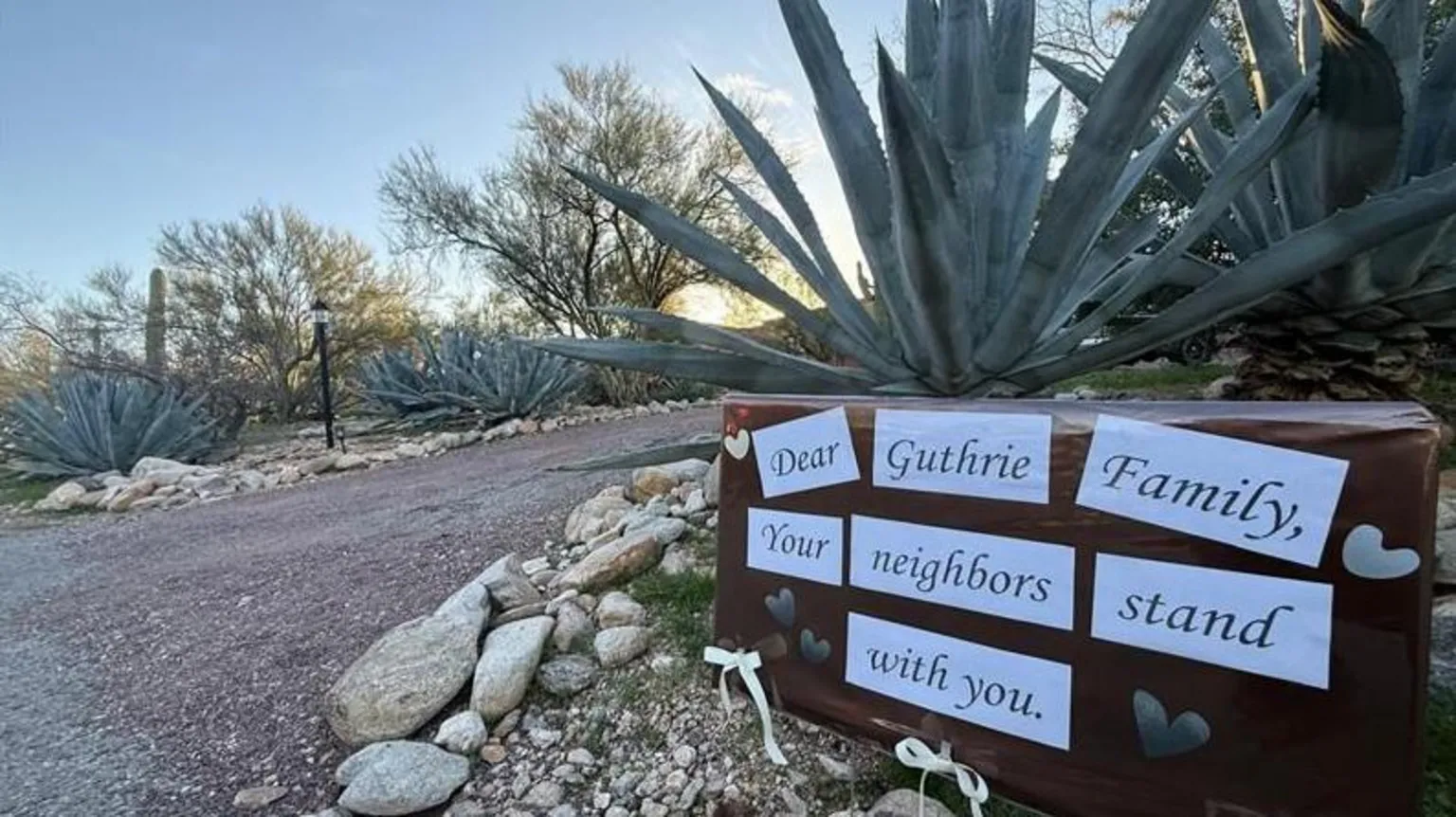 Neighbours have erected signs for the Guthrie family. The sign under a cactus says, 