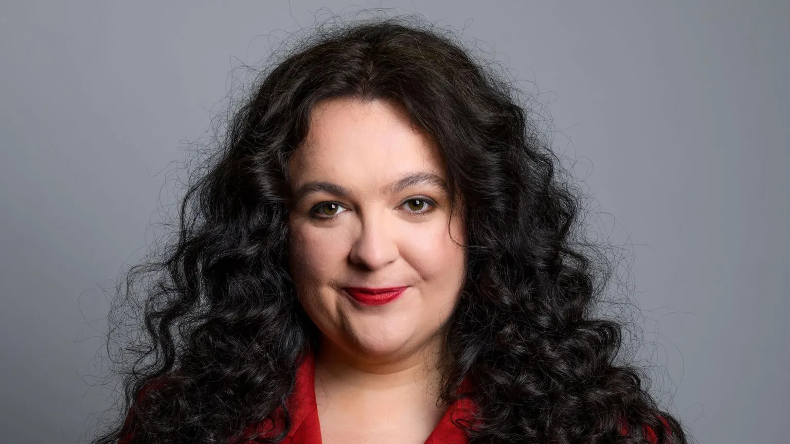 Steve Ullathorne Ashley Storrie, a woman with long dark hair, wearing a red jacket. She is staring into the camera