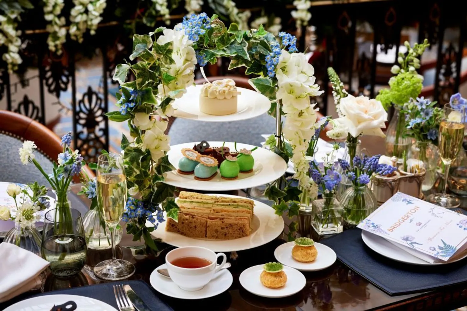 The Lanesborough An afternoon tea spread with a cake stand, cups of tea, pastries, flowers, menus