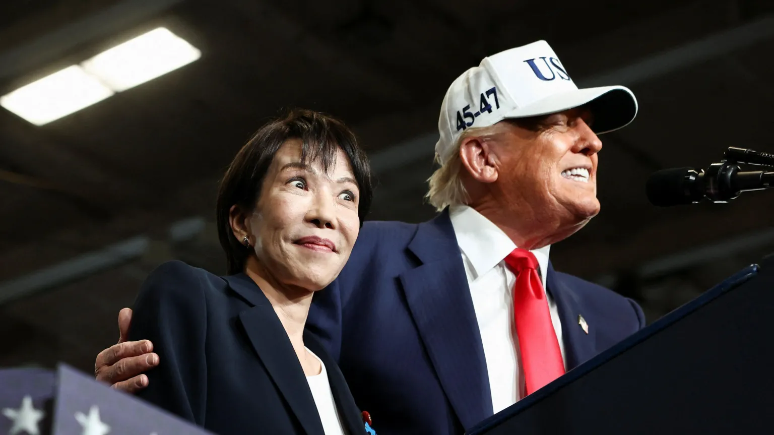  Donald Trump puts his arm around Sanae Takaichi, on stage aboard a US aircraft carrier