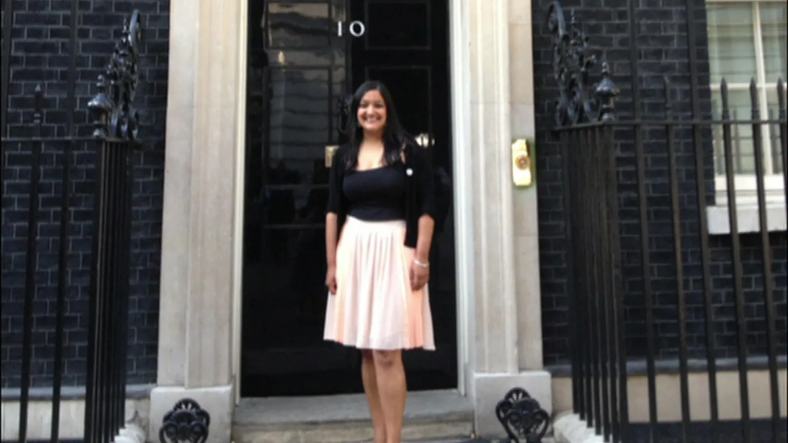 Sanju Pal Sanju Pal, wearing a black top and a light coloured skirt, standing on the steps of the Prime Minister's residence in Downing Street.