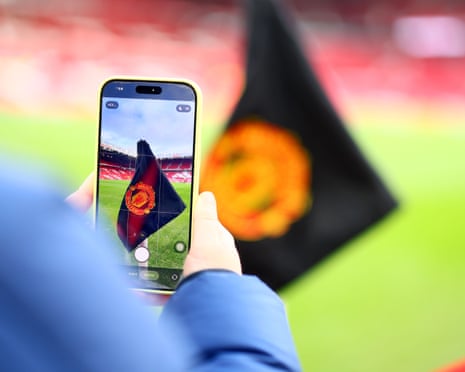 Fan photographing corner flag at Old Trafford during Manchester United match