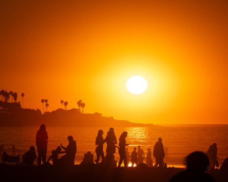 Crowds on La Jolla Shores beach as smoke from the Los Angeles fires settles on the Pacific Ocean at sunset on January 10, 2025 in San Diego, California.