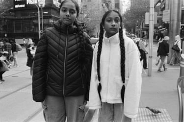 two young girls stand on the street looking to camera