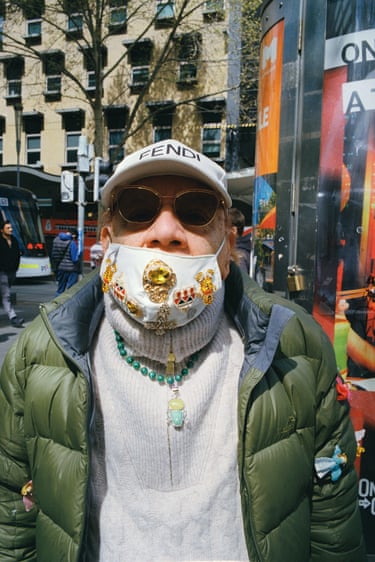 a man looks to camera with a face mask on that is decorated in jewels
