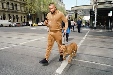 a man walks his dog across the road