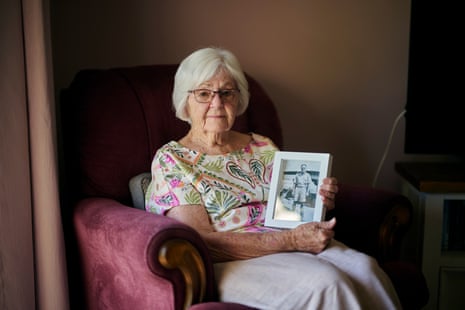 Wilma Spence seated in a chair, holding a framed photograph of her father
