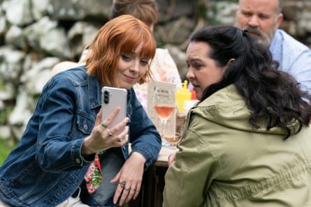 Kat Ronney shows her phone to Ashley Storrie as they sit outside drinking wine