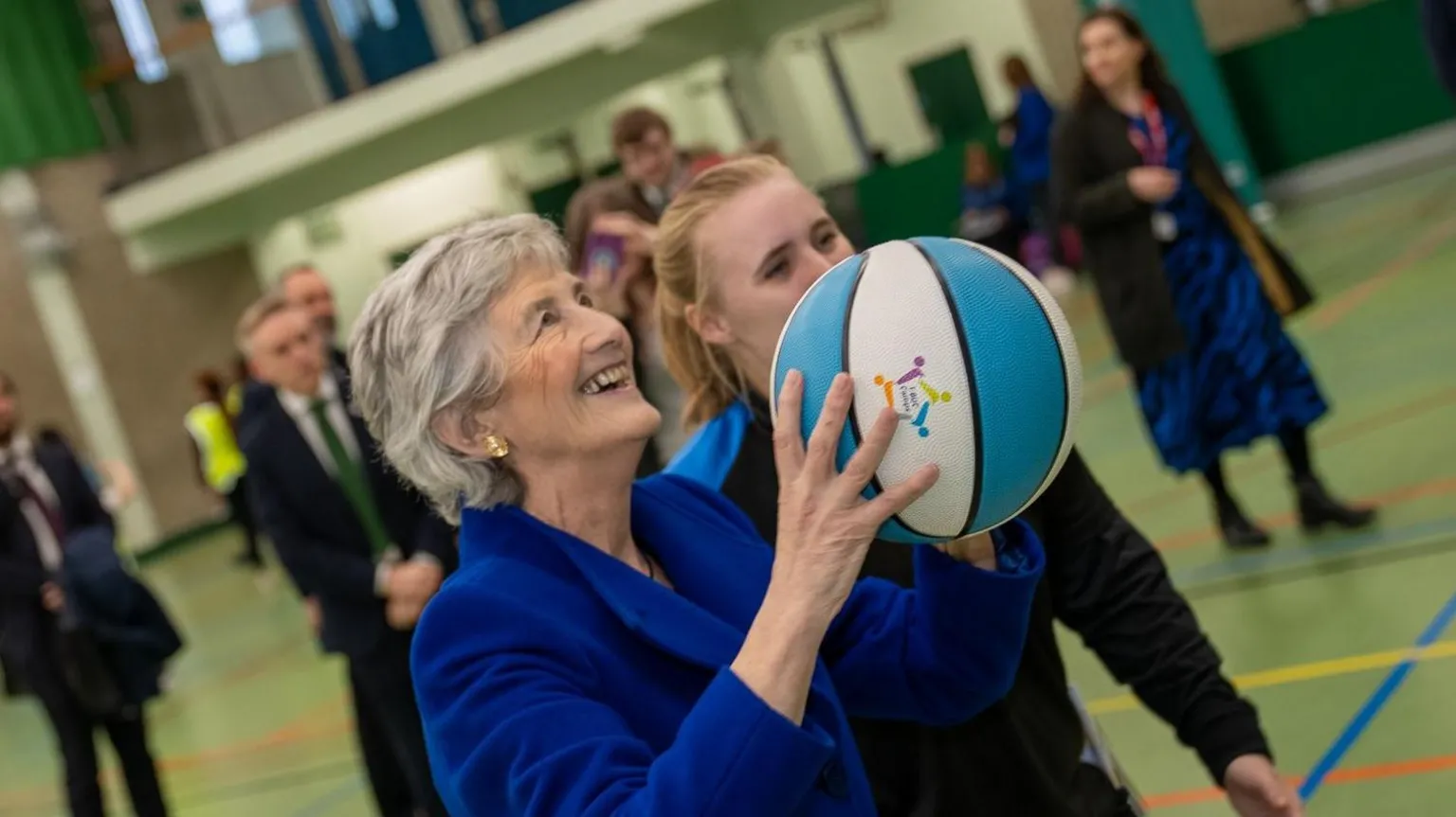 QUB Catherine Connolly holding a white and blue basketball in a sports hall. 