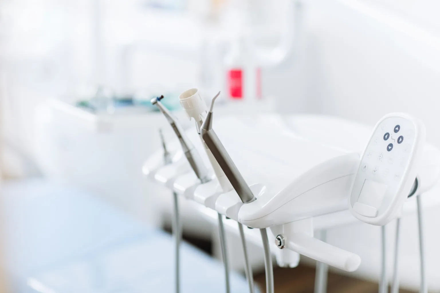  A set of dental tools lined up in a holder next to a dentist's chair