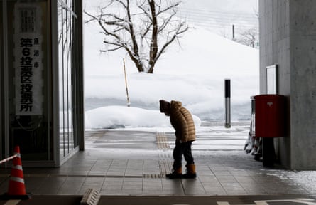 A voter at a polling station in Uonuma, Niigata prefecture with snowy fields in the background