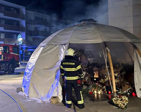 Firefighters at memorial partially covered by blackened tarpaulin dome