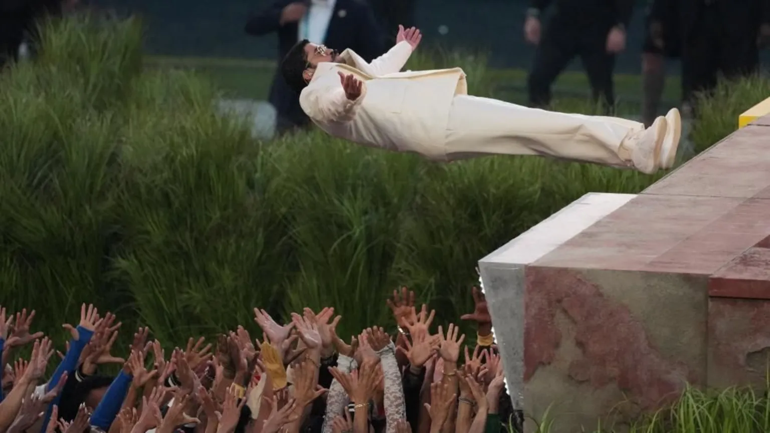 Reutes Connect Bad Bunny falls backward from a platform into a crowd of dancers holding up their hands to catch him as he performs at halftime in Super Bowl LX 