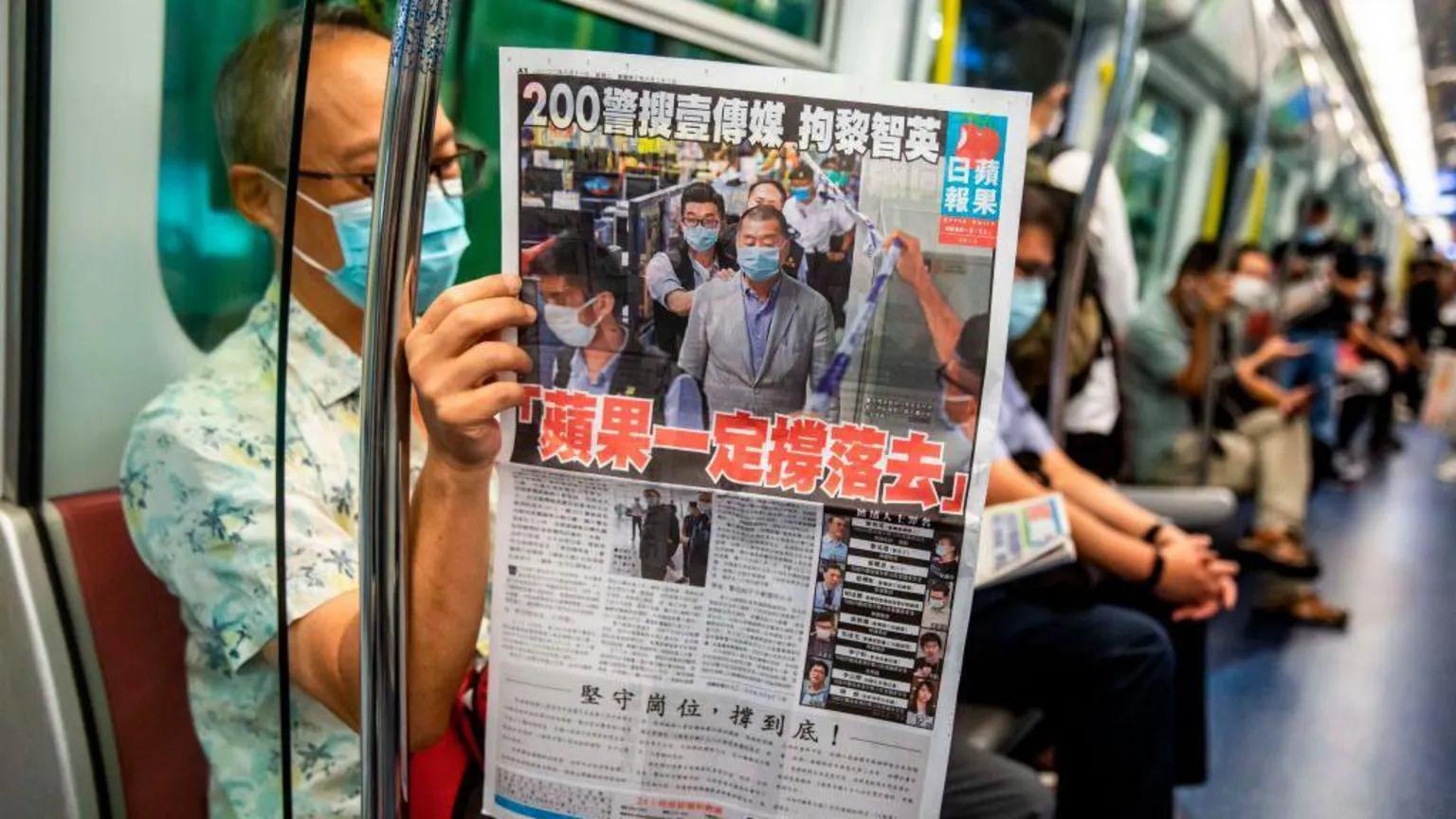  A man reads a copy of the now-defunct Apple Daily newspaper on a train in Hong Kong on 11 August, 2020, one day after authorities searched the newspaper's headquarters. 