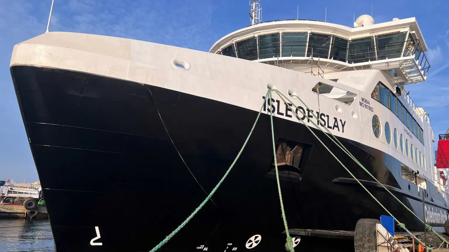 CMAL A black and white ship with Isle of Islay written on the side, moored by a quayside
