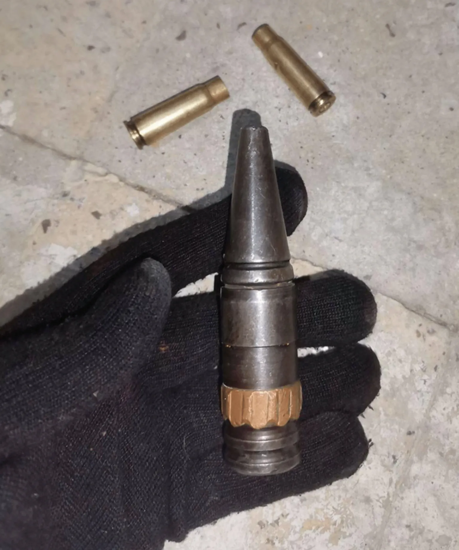 Mamlekate A screen grab from a verified video shows a black-gloved hand displaying a large black spent 20mm automatic cannon-round shell, with rifling marks on its driving band, while two spent cartridge casings from a Kalashnikov AK-47 assault rifle lie on tiling underneath.