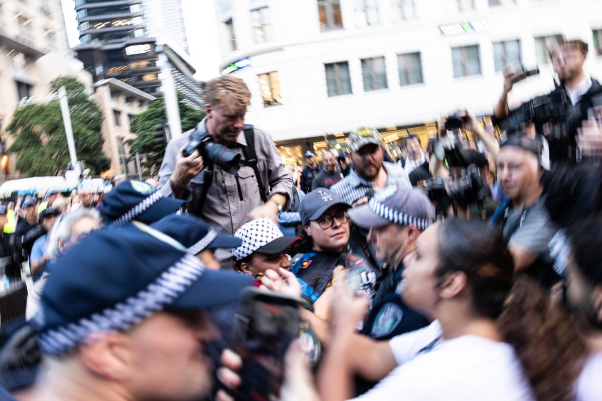 A woman (centre) is grabbed by police and taken from the crowd after staging a lie-in at Sydney’s Town Hall last night.