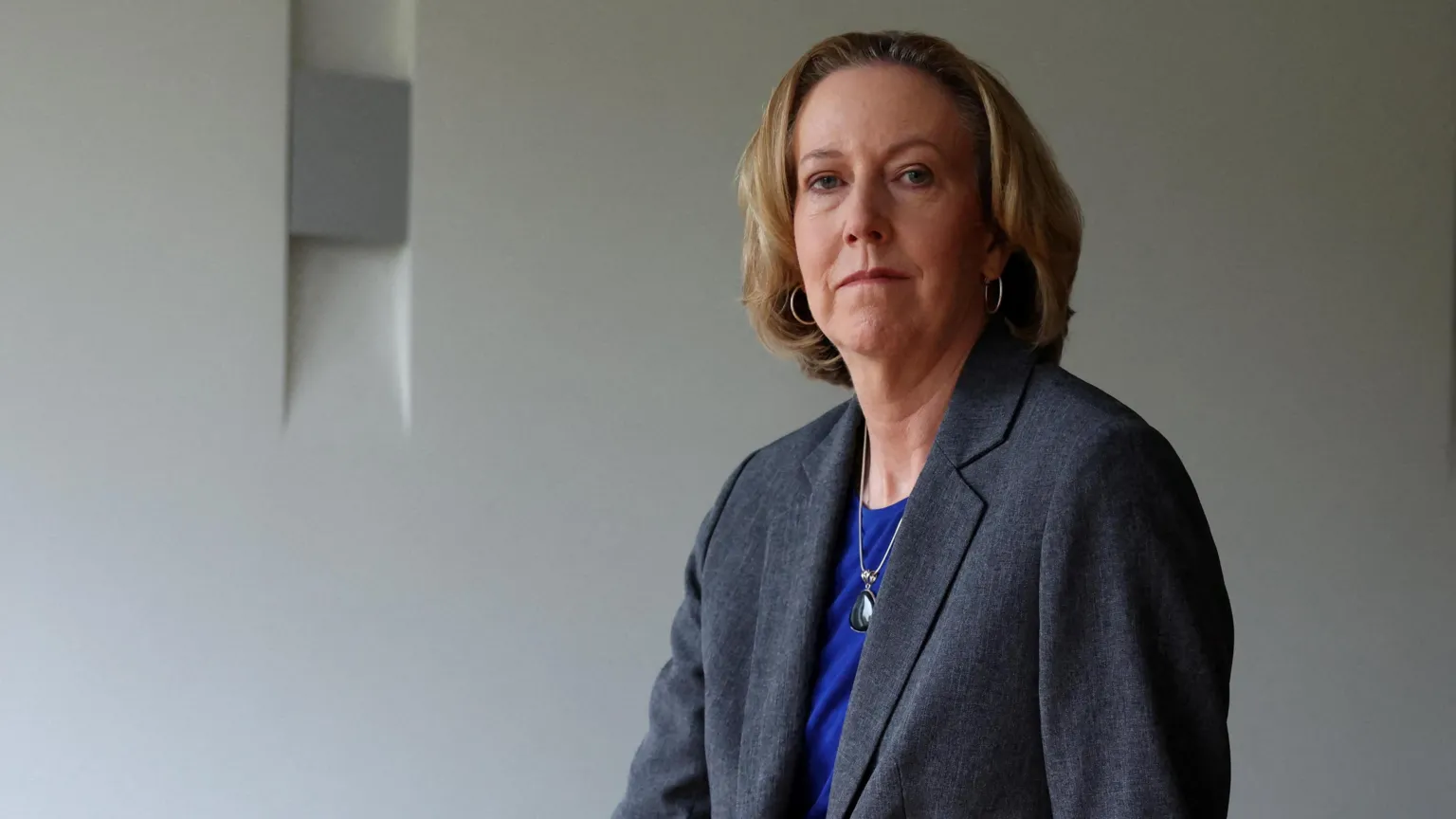  Newly appointed BP chief executive Meg O'Neill wears a grey suit and blue top while posing sat on the edge of a boardroom table.