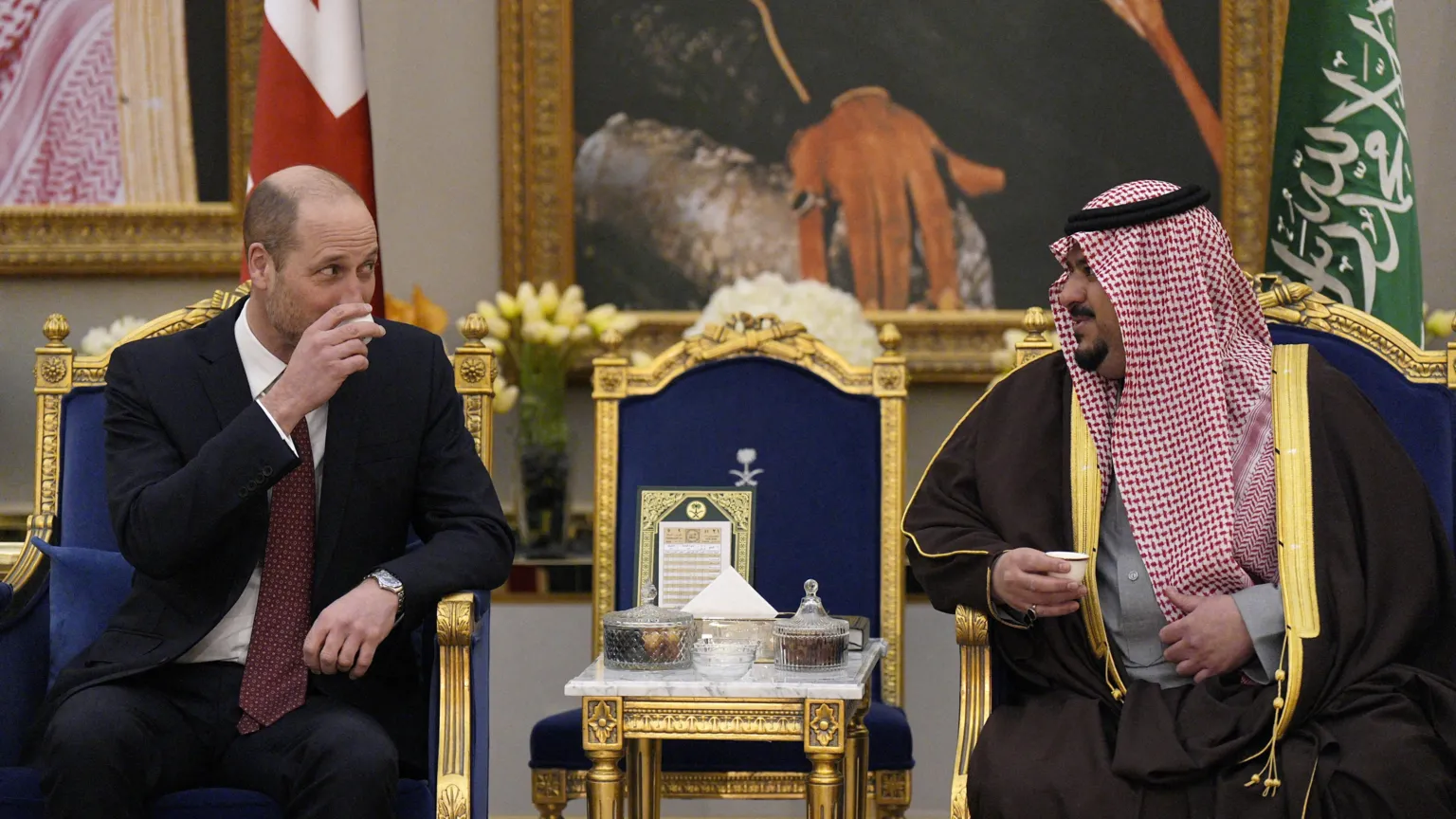  Prince William sits on a blue and gold seat and drinks from a small ceramic cup with Deputy Governor of Riyadh Region, Prince Mohammed bin Abdulrahman bin Abdulaziz. 