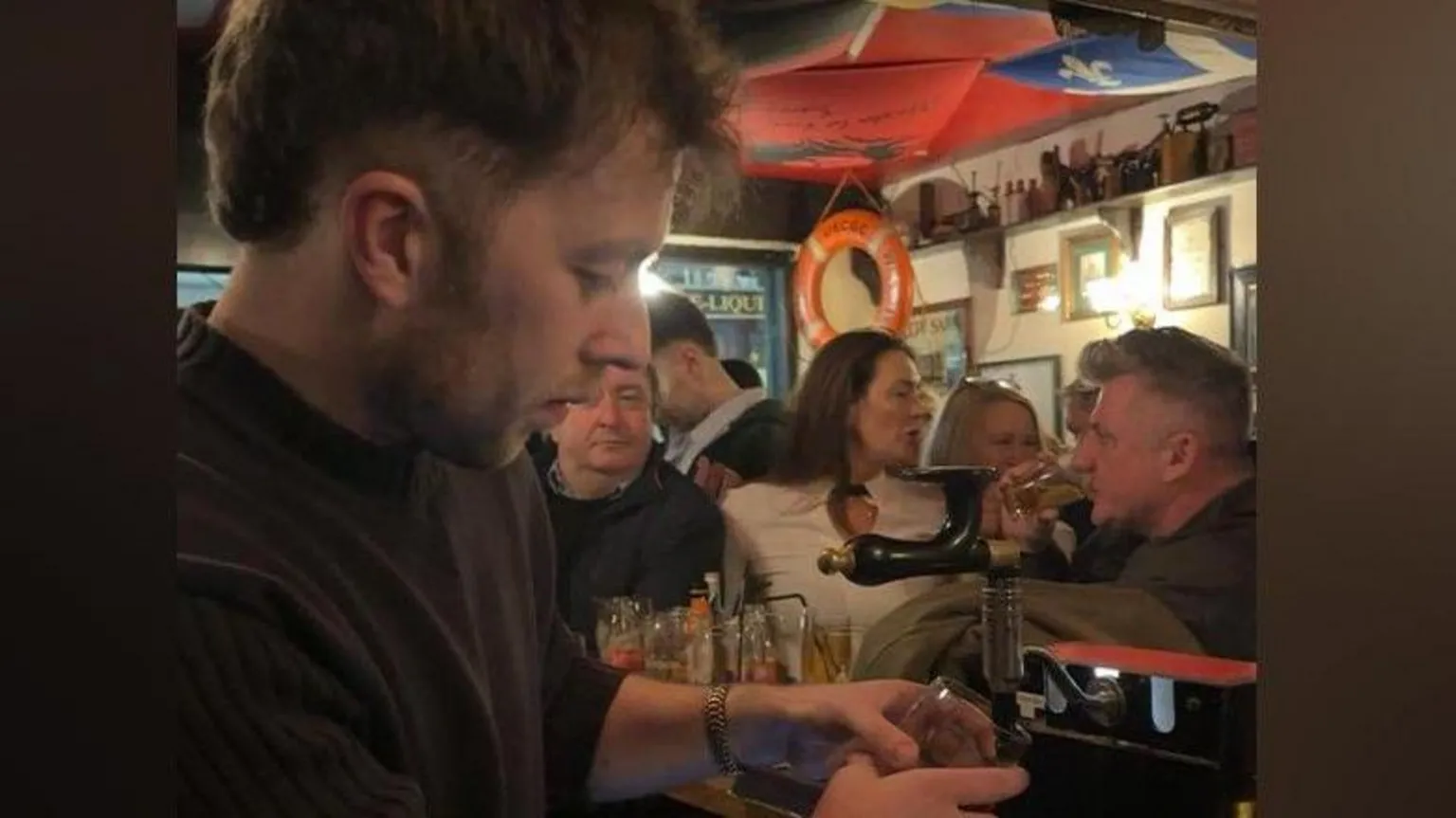 Peadar O'Donnell's A man stands behind the bar in a packed pub as he poura pint. A number of patrons can be seen in the background of the image.