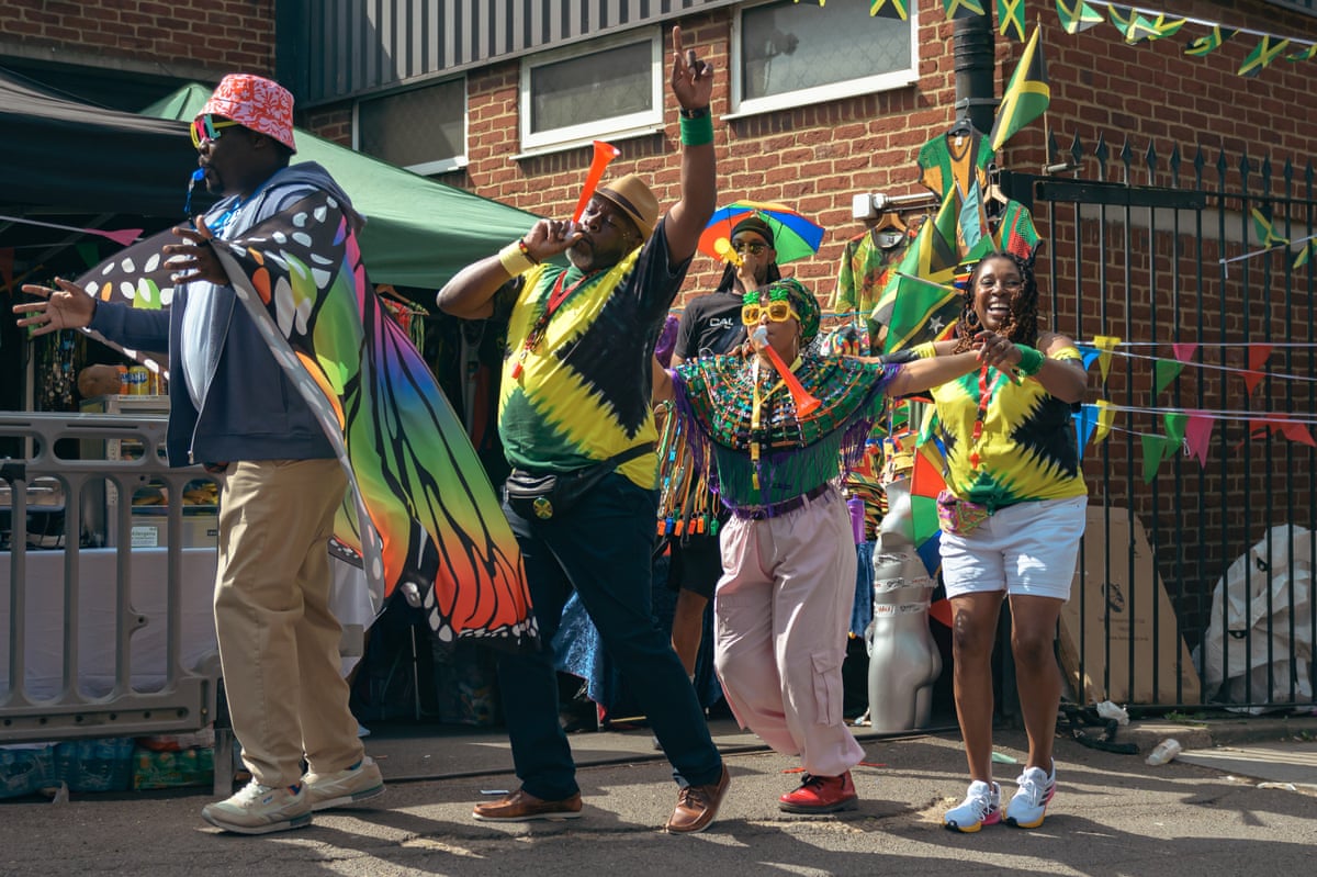 People dressed in colourful butterfly capes and hats, dancing on a council estate