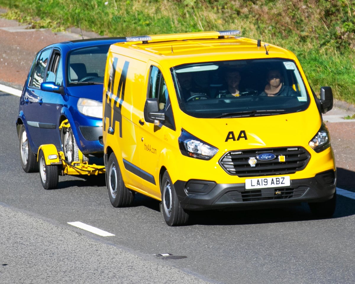 An AA van tows away a broken down car