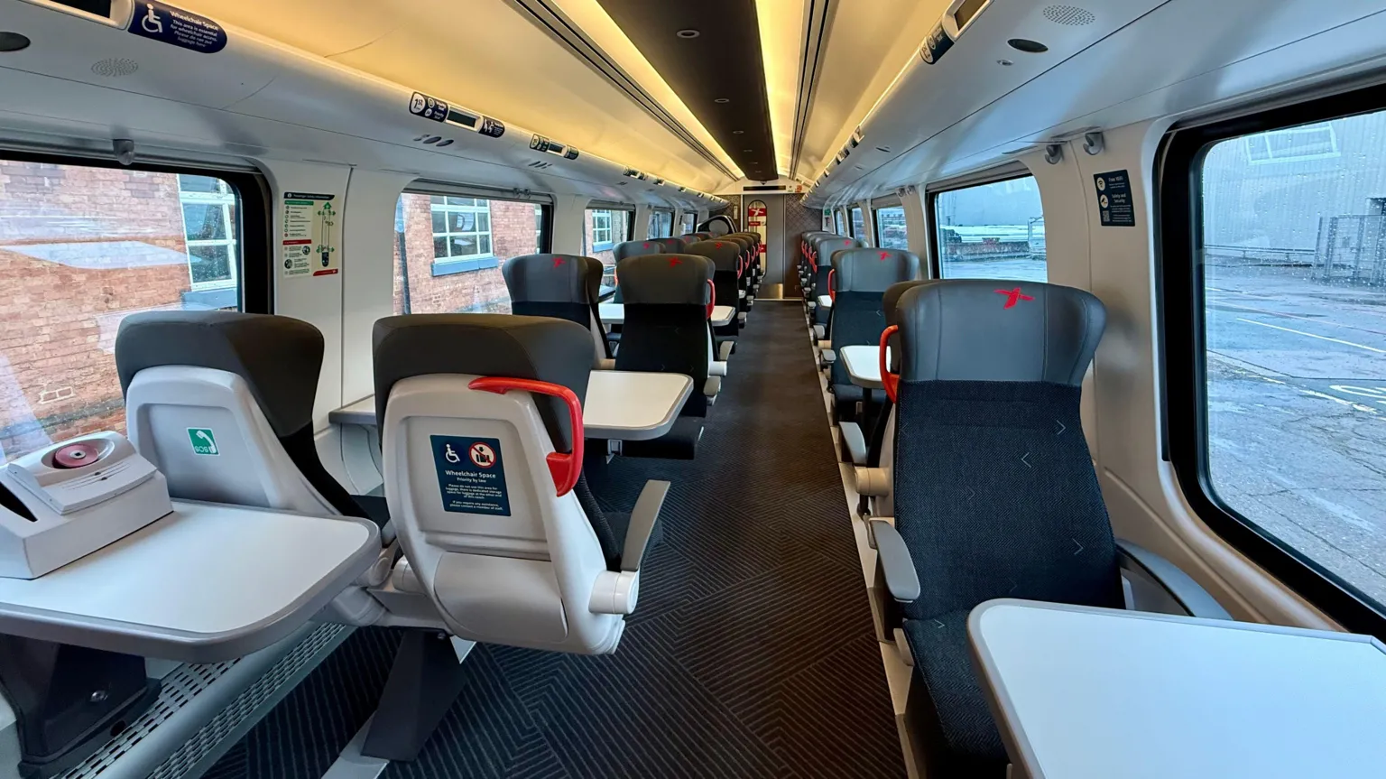 CrossCountry The inside of what appears to be a first class carriage of a refurbished CrossCountry Voyager train. There are group seats with tables on one side of the train and a row of indivudal seats with tables on the other.