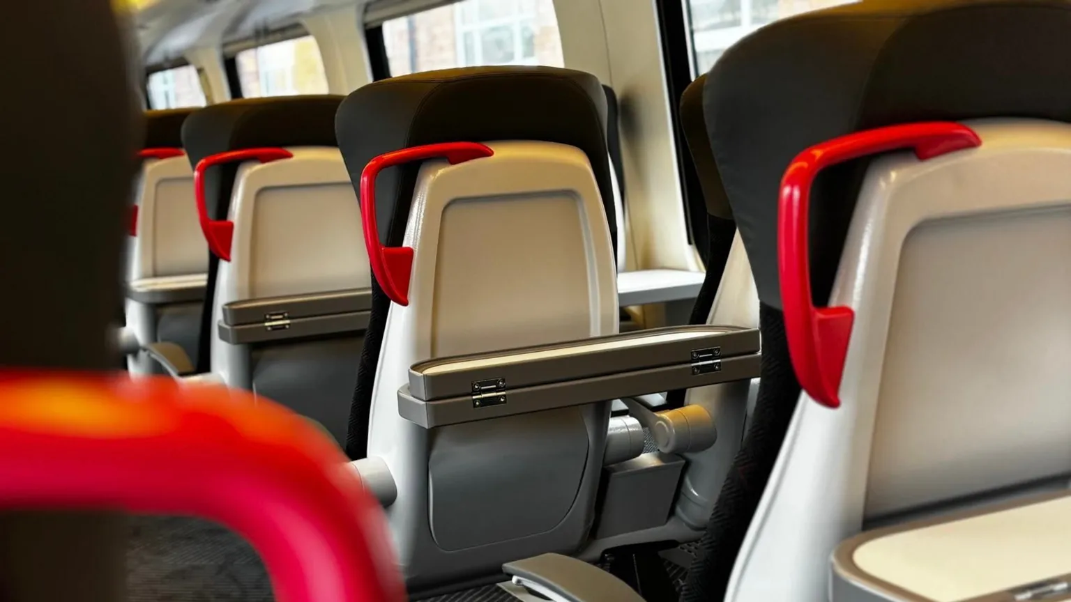 CrossCountry Image shows refurbished seats on the Crosscountry Voyager train. The seats are made out of black fabric and have red handles for stability.