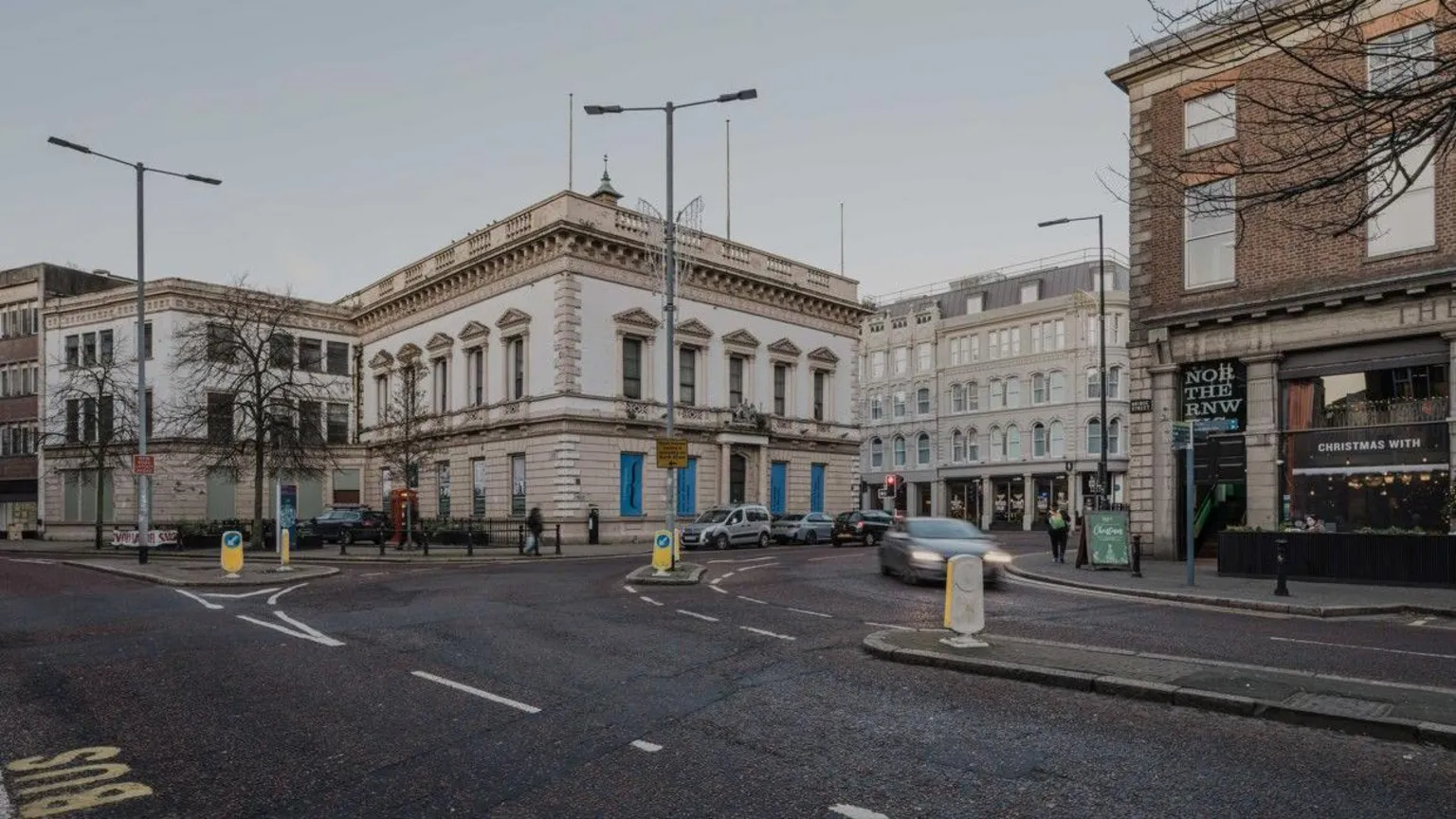 The World Monuments Fund A building across a road. Some cars are driving 