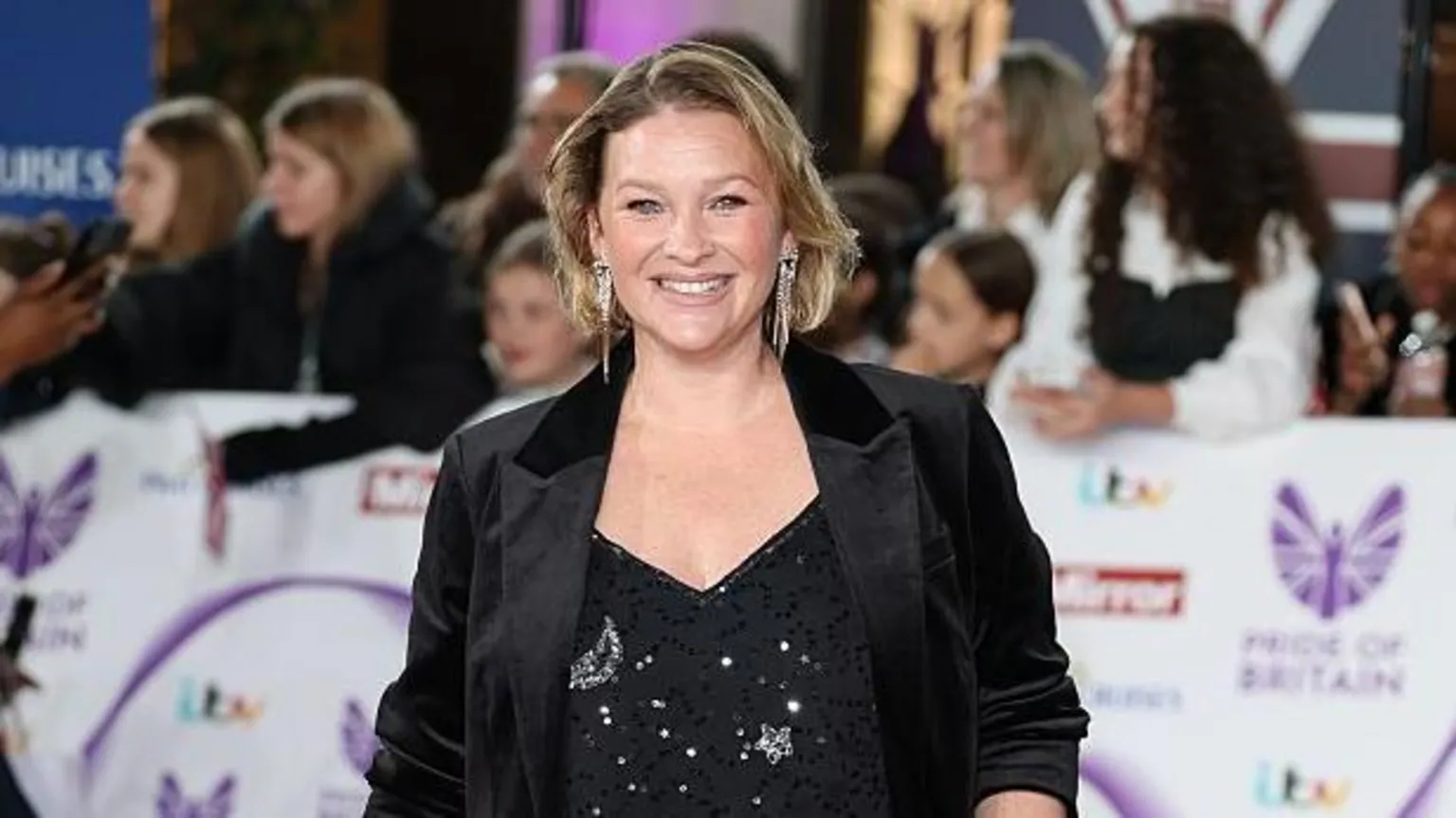  Page at the TV Choice Wards. She's smiling at the camera and is wearing large sparkly earrings, a black sparkly top and black blazer jacket. Her dark blonde hair is cut in a bob.