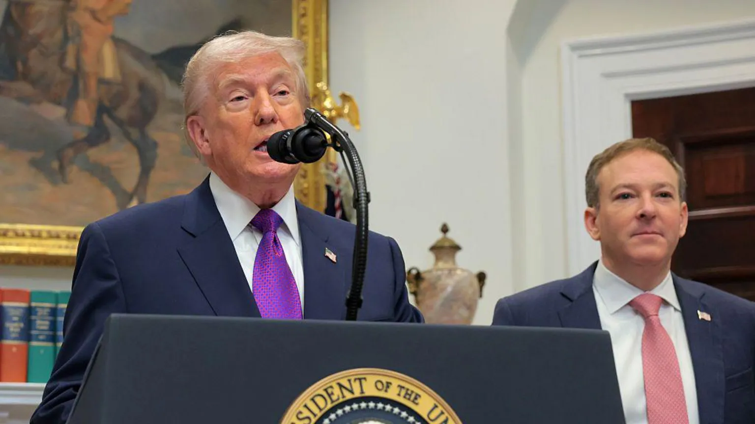  Donald Trump and the EPA's administrator Lee Zeldin - Trump is speaking behind a lectern in the Oval Office while Zeldin is standing off to the side wearing a salmon coloured tie 