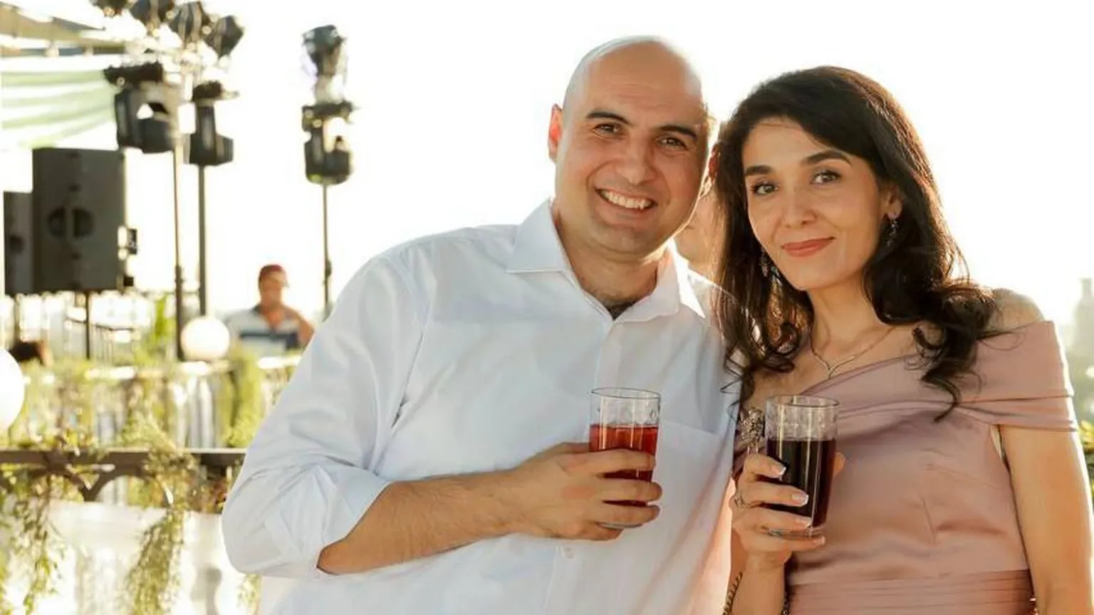 Zafar Khallyev Zafar and Dilya are pictured enjoying a drink together. He's wearing a white shirt. Dilya is in a soft pink silk off-the-solder top. She has long brown hair. 