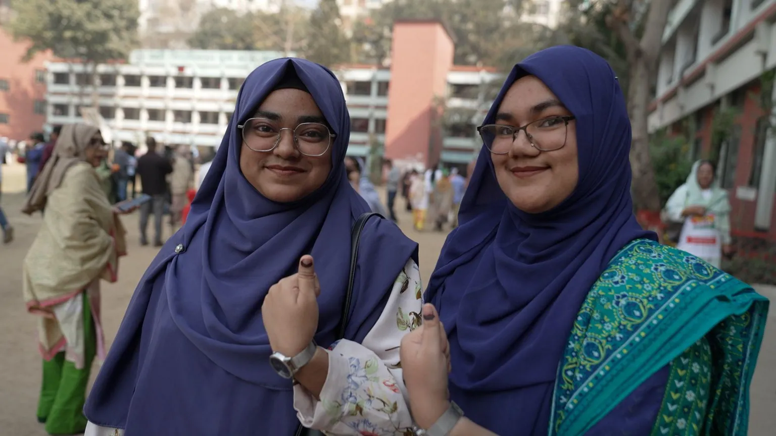 Sanjay Ganguly/BBC A couple of young women in Bangladesh smile and give the thumbs up sign
