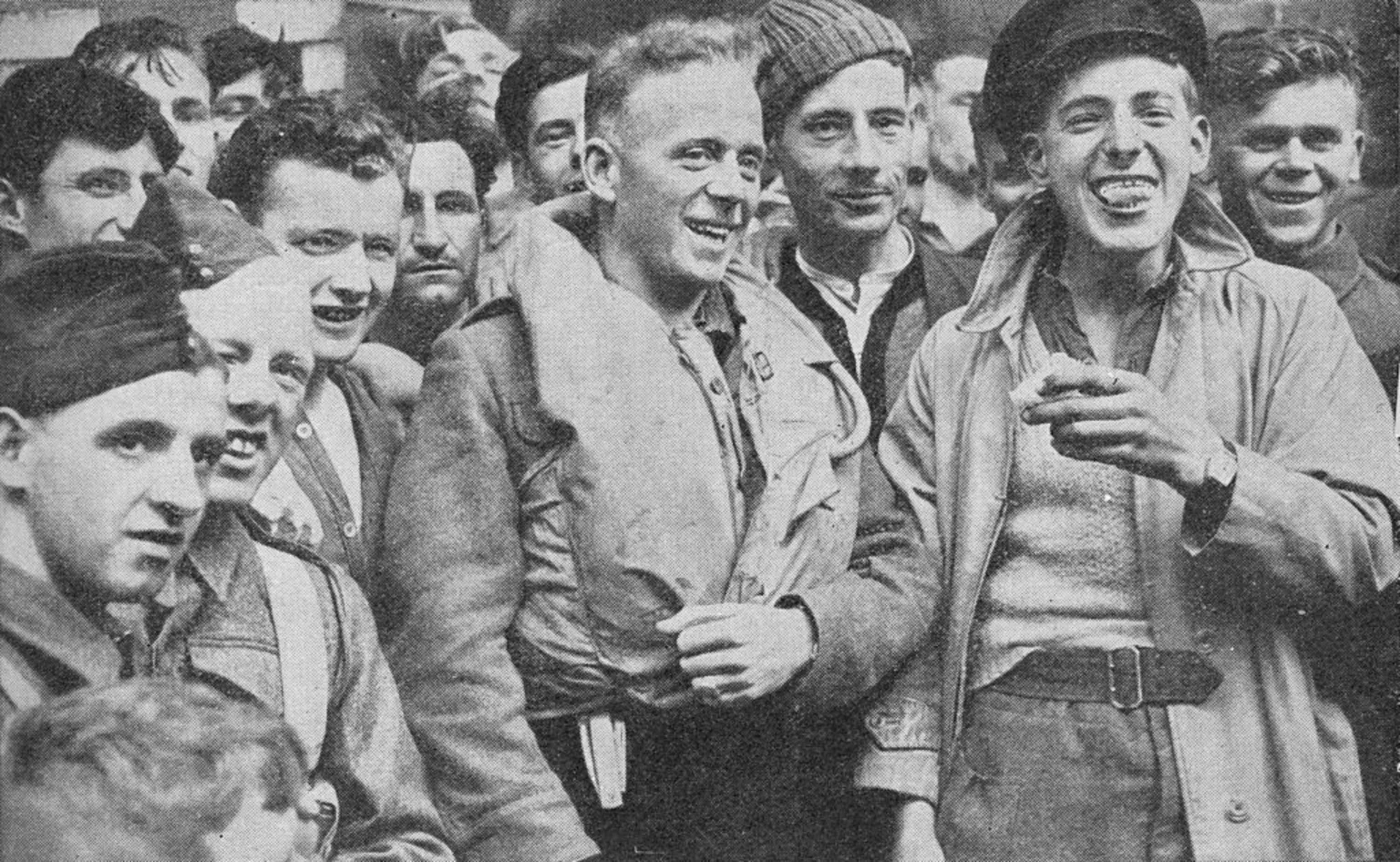  A black and white image of survivors of the Arandora Star sinking. Some are still in life jackets. Many of them look happy and relieved.
