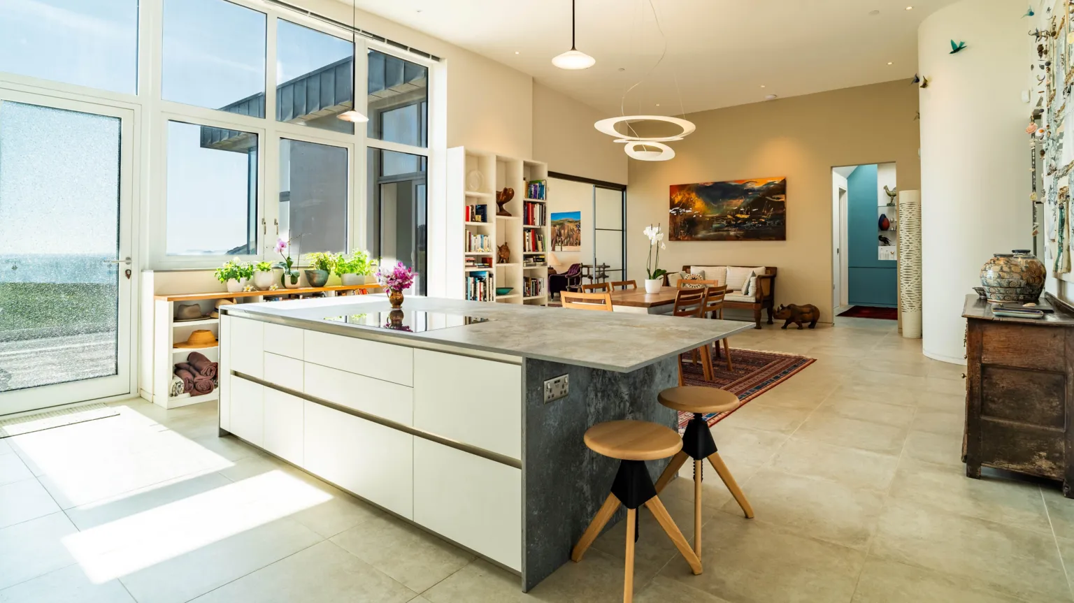 Fine & Country A modern open-plan kitchen and living area with large windows overlooking the ocean. 