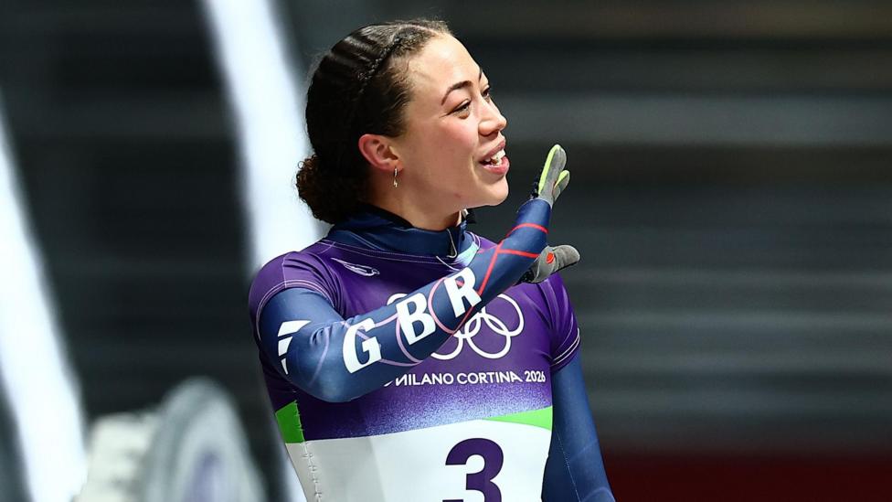 Tabitha Stoecker waving to friends and family in crowd at Cortina sliding centre