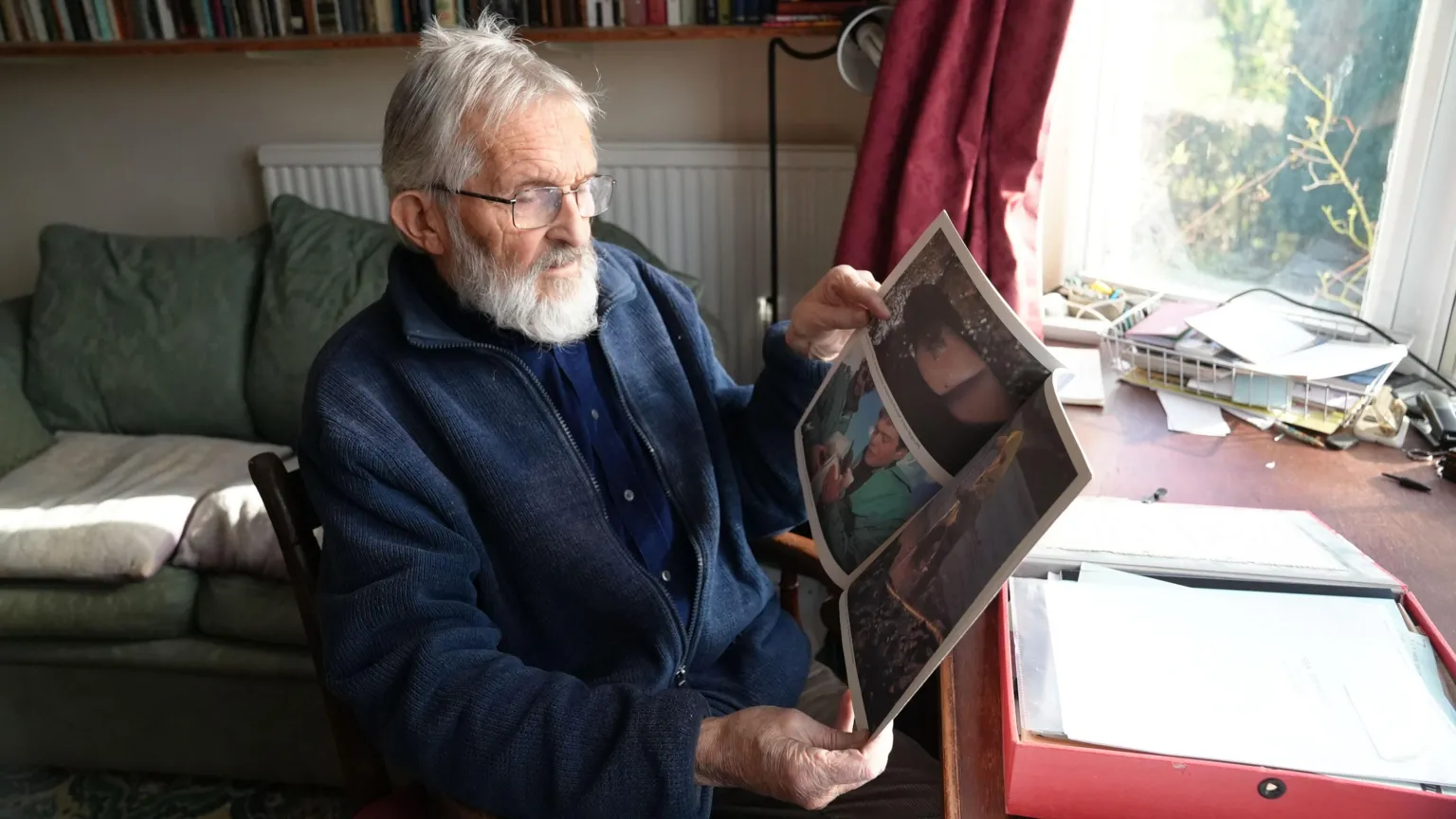 Gordon James, ex director of Friends of the Earth Cymru sat at his desk looking through documents and pictures from the time of the Sea Empress disaster