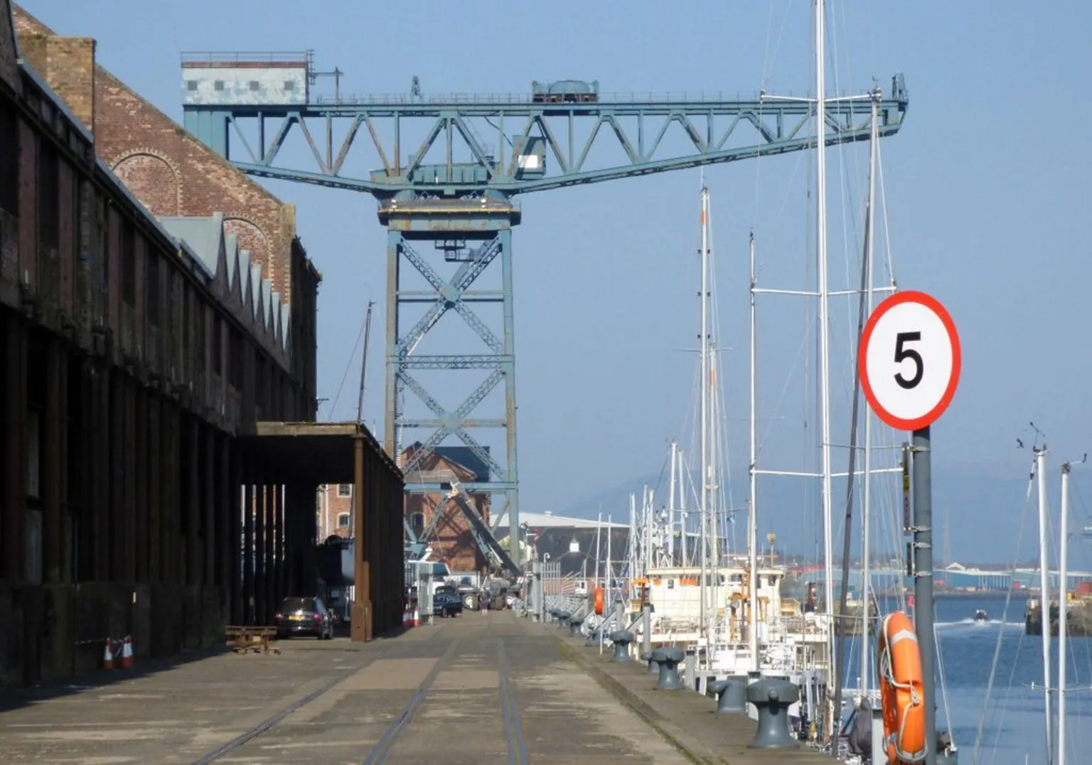 Geograph/ThomasNugent A large blue crane at a dock with ships moored at the quayside