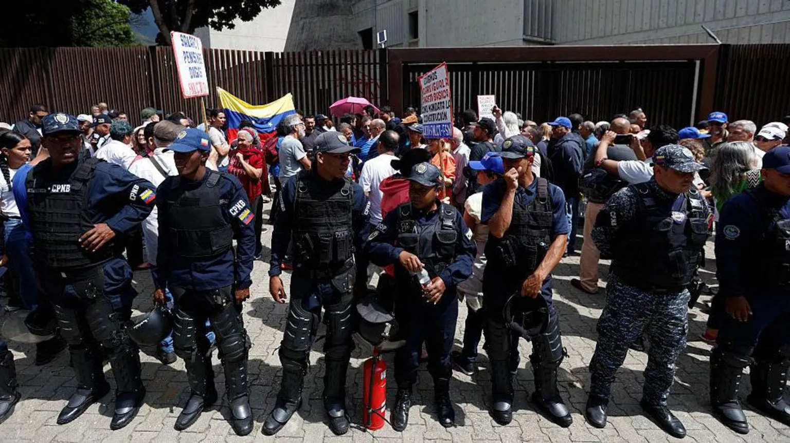 AFP via Venezuelan policemen stand in front of a protest in Caracas over low wages