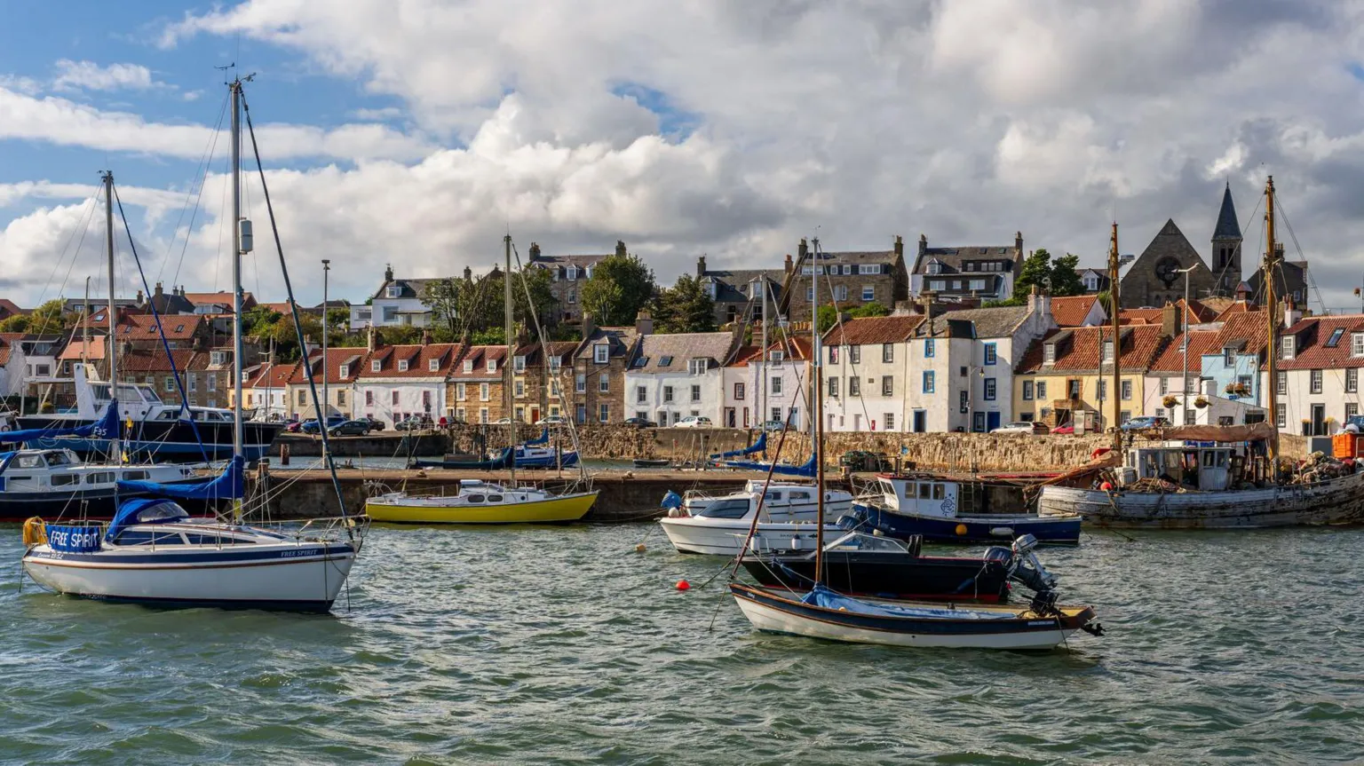  St Monans is a bright fishing village with colourful houses by a harbour with boats bobbing in the water