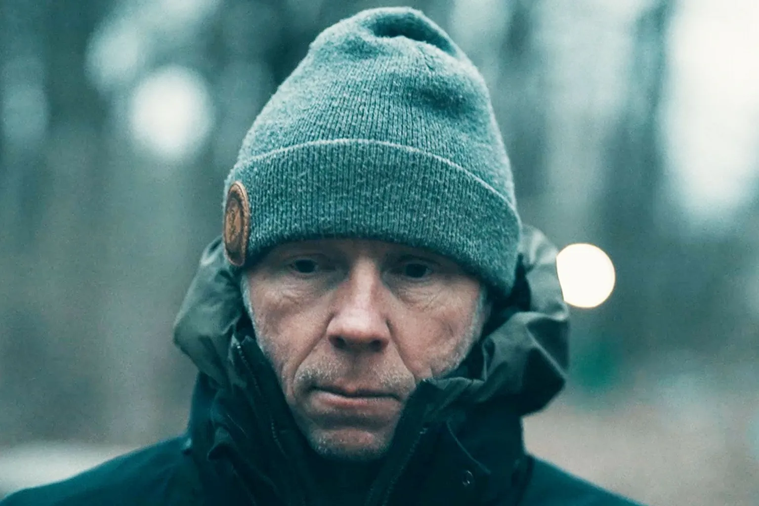 Greg Squire on a walk in the woods - he is wearing a dark coat and grey beanie hat.