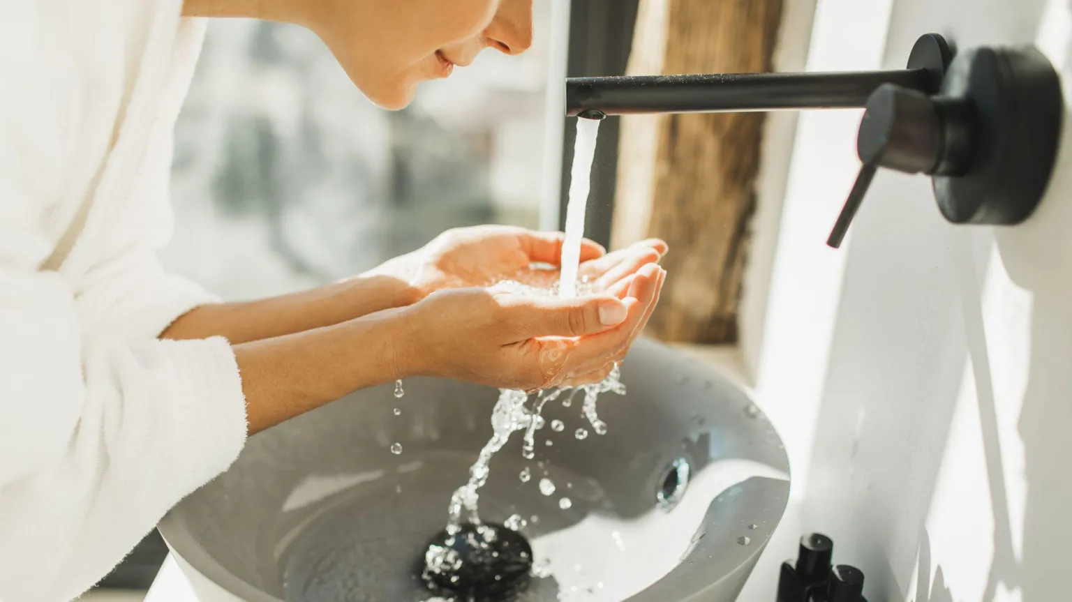  Young woman awakening, washing and cleaning her face with splashing wate