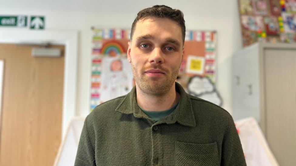 Mabon Huws yn gwisgo crys gwyrdd