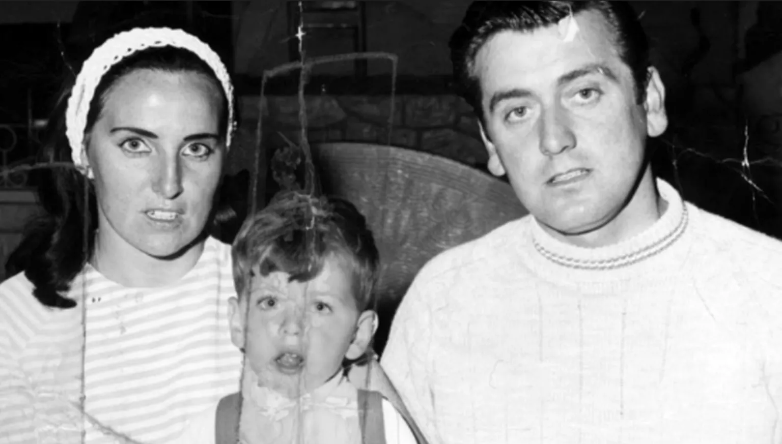 Peter Cunnah Shows a woman on the left with dark hair and white headband, wearing a horizontally-striped top. On the right is a man with dark hair combed back and wearing a light-coloured jumper. In between them is a boy with fair hair and a light-coloured top.