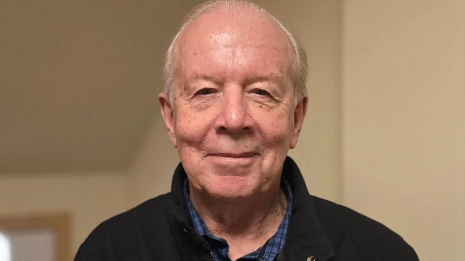 Chris Robertshaw, wo has receding short grey hair and is wearing a blue checked shirt under a black jacket.