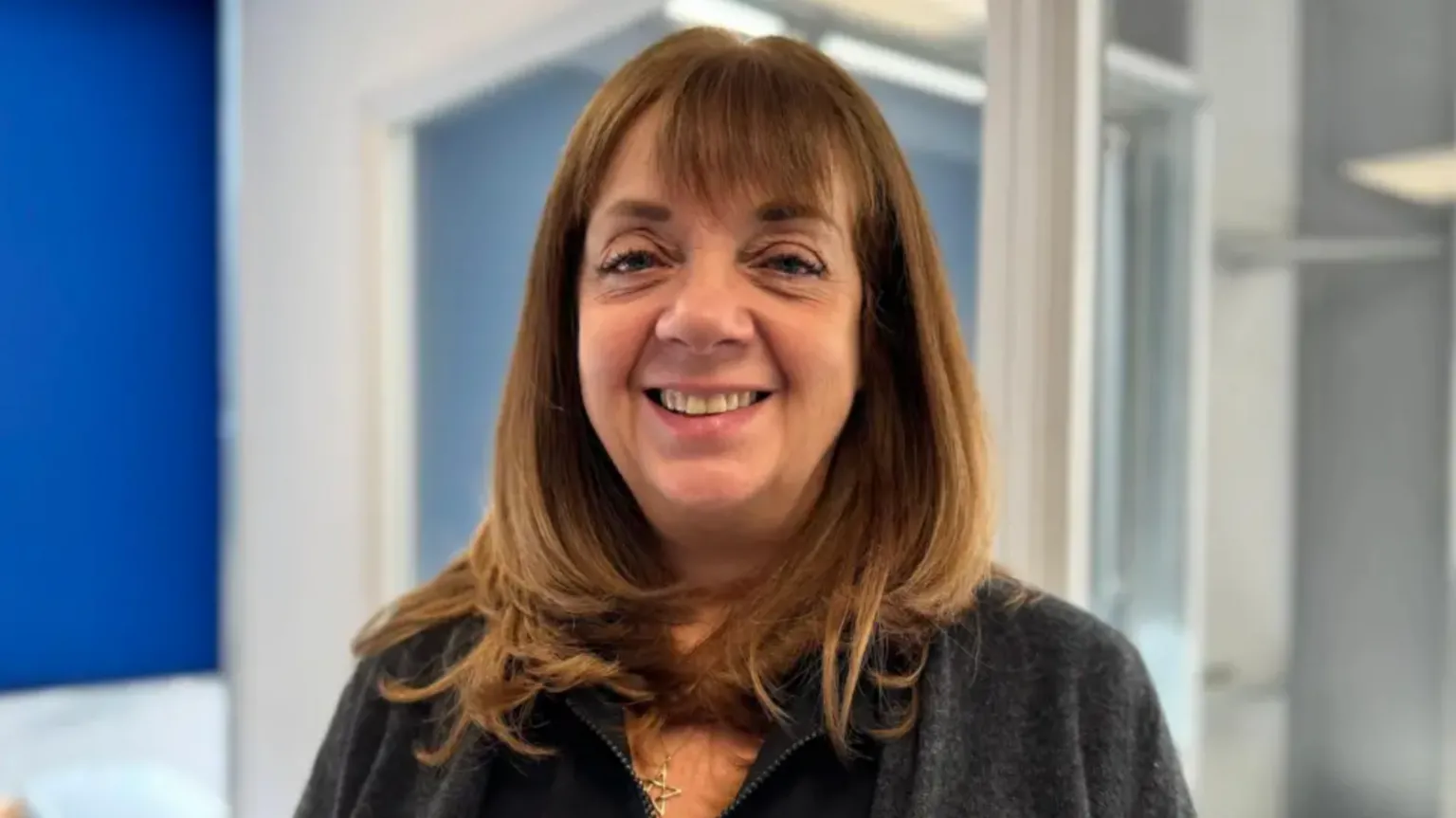 Jackie Betteridge smiles at the camera. She has long brown hair.