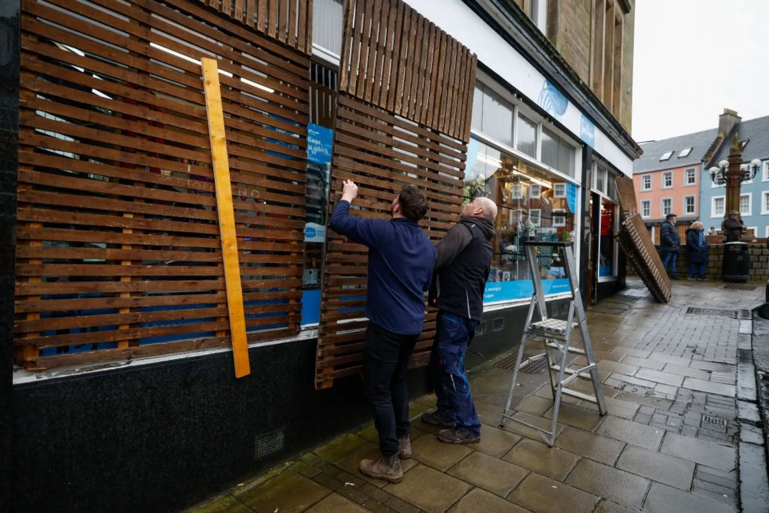  Two men fit boards to a shop front ahead of the Jedburgh ba game